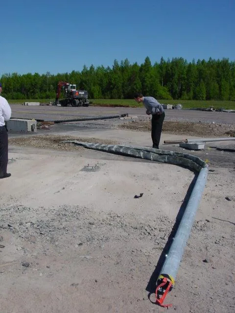 The folded pole lying on the test field with people inspecting it.